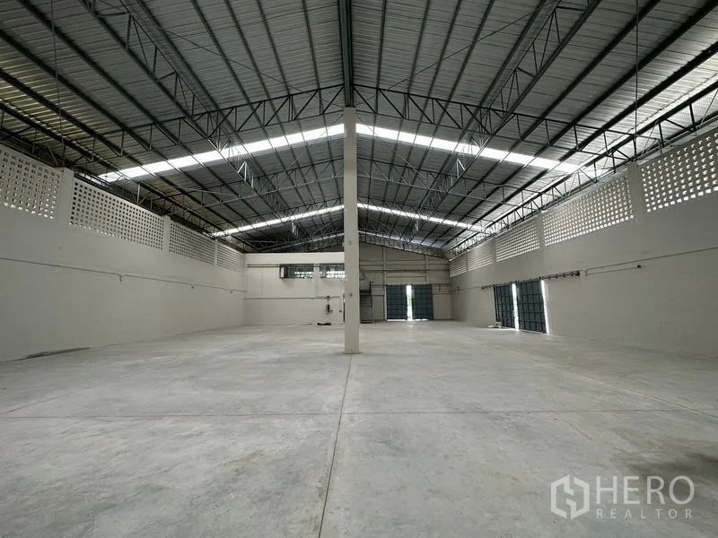 Factory for rent in Lam Luk Ka, Pathum Thani - Open warehouse bay with central column and several roller shutter doors.