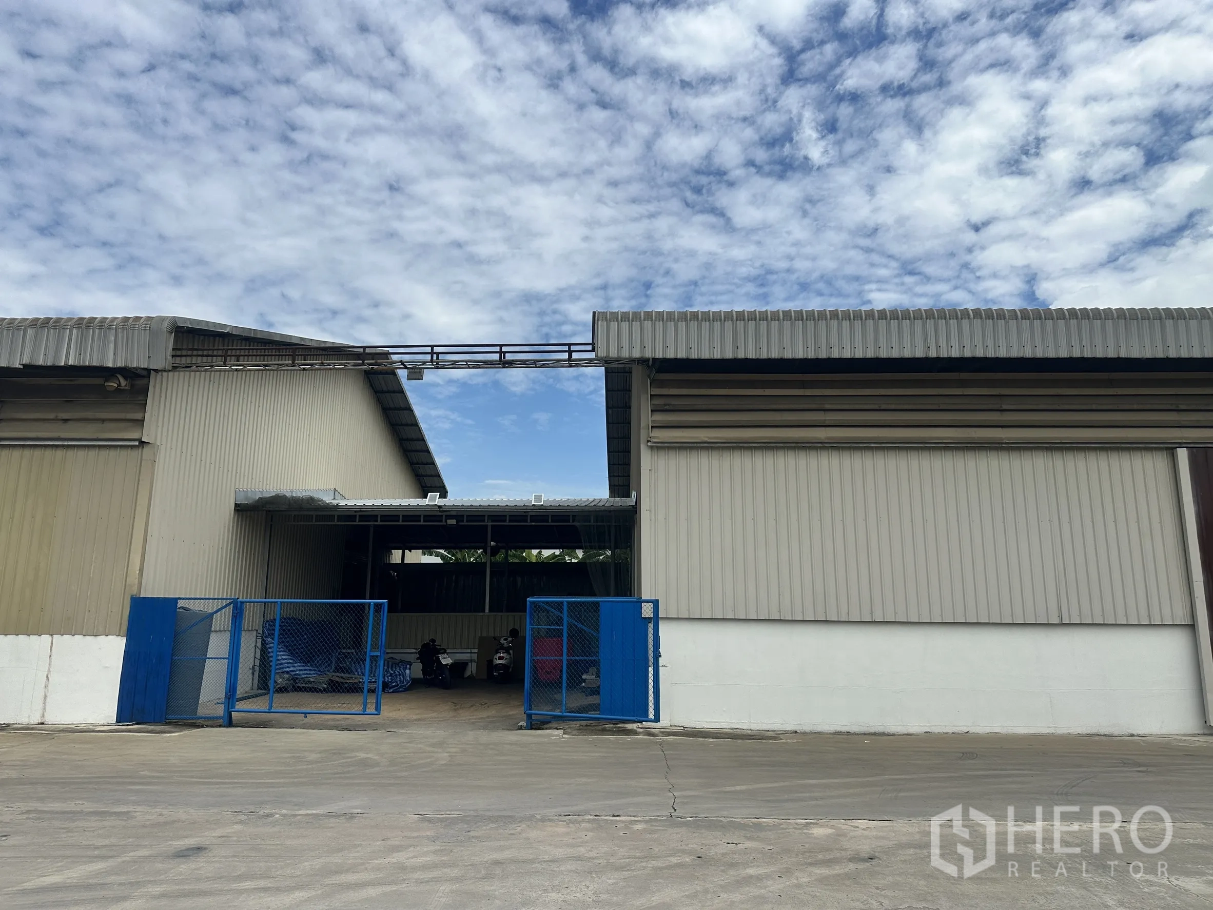 Factory for rent in Lat Krabang, Bangkok - Blue gated service entrance between two metal-sheet buildings in the complex.
