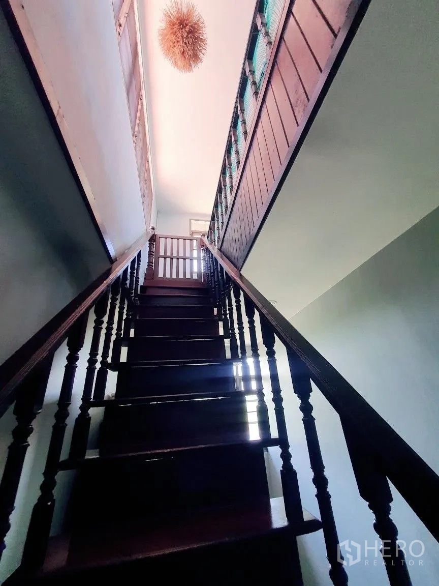 Warehouse for rent in Lam Luk Ka, Pathum Thani - Polished wooden staircase leading to the upper floor with a hanging light.