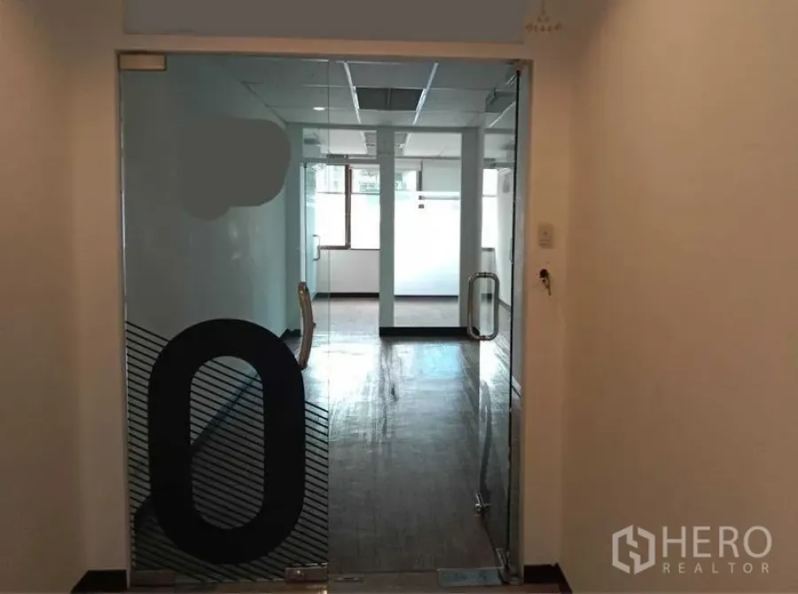 Office Space for rent in Watthana, Bangkok - Glass double-door entrance leading to a bright office area with pillars and windows.