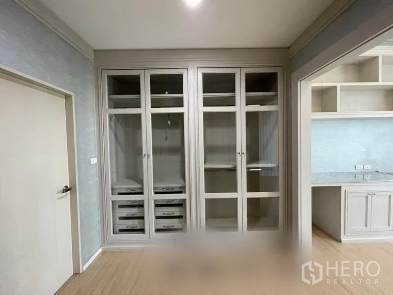 Townhouse for sale in Suan Luang, Bangkok - Wall of glass-door closets and shelving opposite built-in worktop in a bedroom suite.