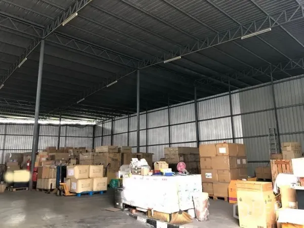 Warehouse for rent in Pak Kret, Nonthaburi - Open-plan storage area with high metal roof, shelving space and palletized goods.