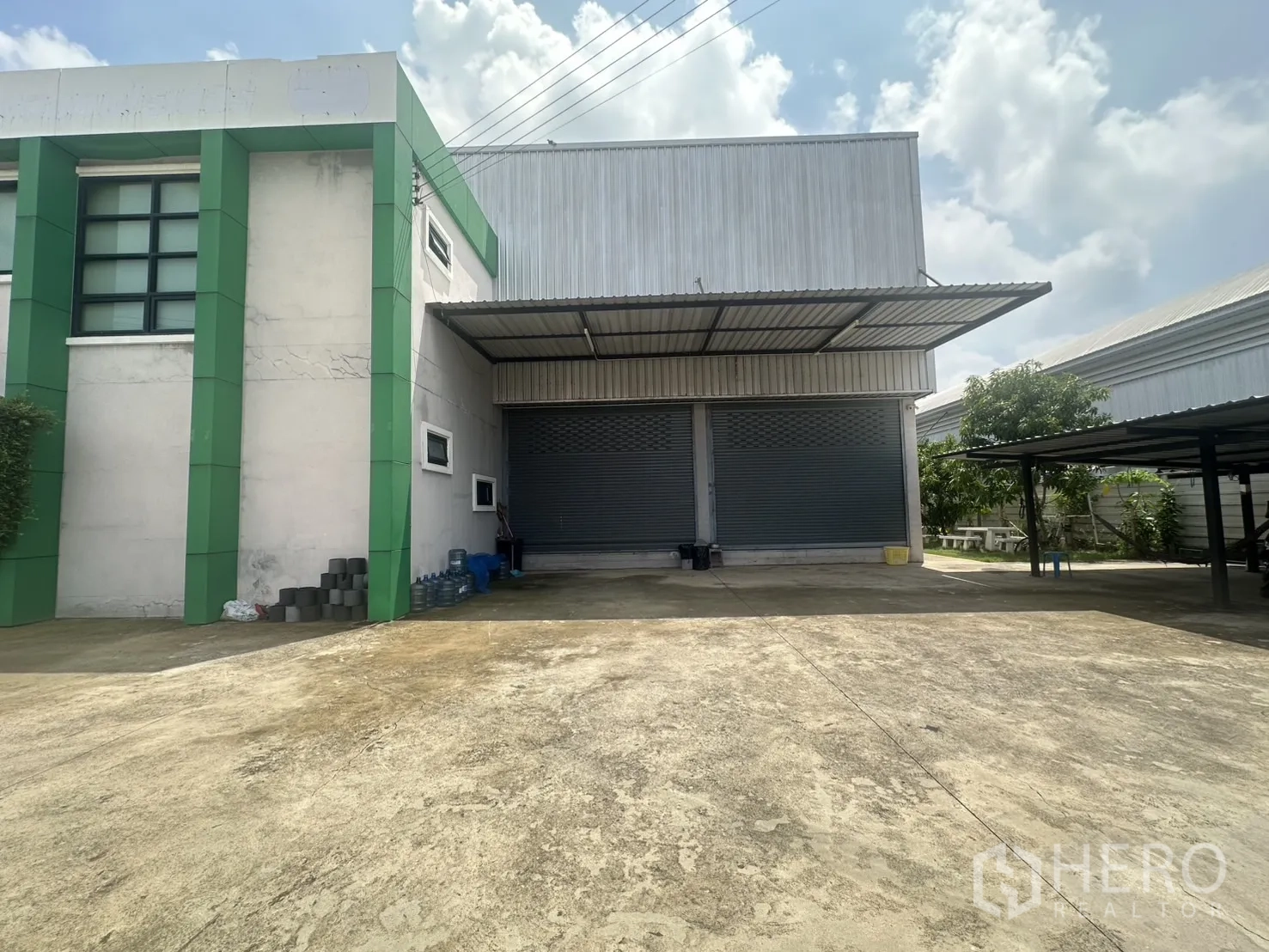 Warehouse for sale in Bang Len, Nakhon Pathom - Warehouse frontage with two large roller shutters under a metal awning.