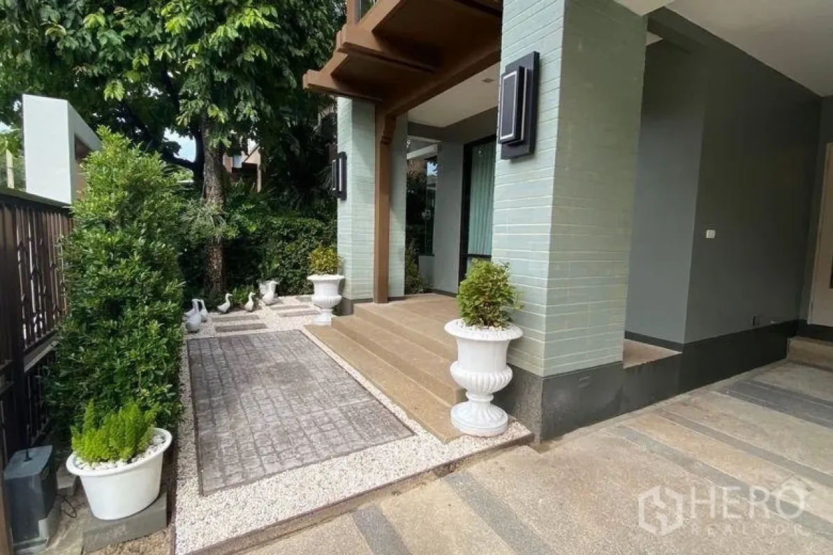 Detached House for rent in Sai Mai, Bangkok - Front entrance with covered porch, planters and a paved walkway leading to the carport.