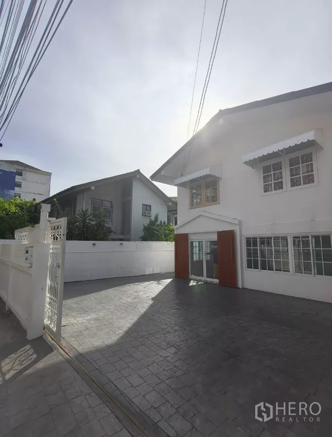 独立式住宅 出租在Bang Na, Bangkok - 带大门的前庭与铺装车位，白色围墙环绕的独栋住宅。