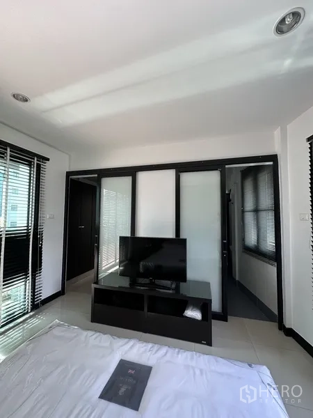Condominium for rent in Khlong Toei, Bangkok - Bedroom view with TV console and sliding glass doors to closet or ensuite.