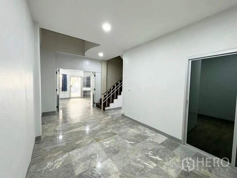 Townhouse for rent or sale in Suan Luang, Bangkok - Corridor with marble flooring, sliding doors and stairs at mid-house