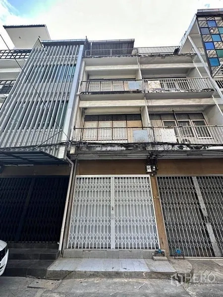 Shophouse for rent in Khlong Toei, Bangkok - Multi-storey row shophouse exterior with balconies and metal gates on a narrow lane.