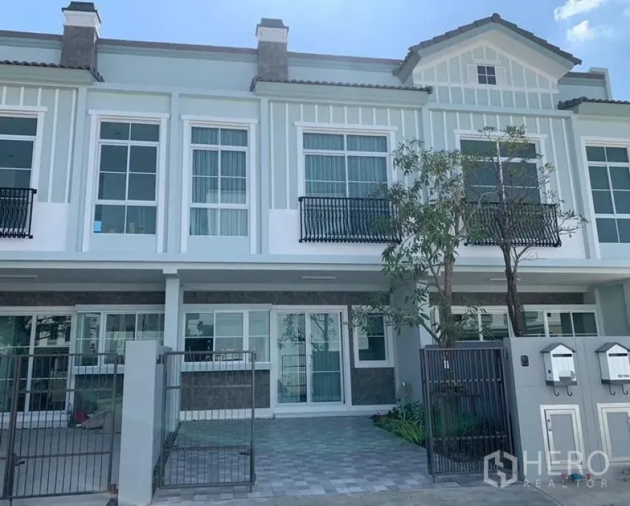 Townhouse for rent - Two-storey townhouse facade at Indy 2, Prawet with gated driveway, balconies and large windows.