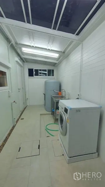 Townhouse for rent - Enclosed utility area with washing machine, sink, water tank, and skylight roof.