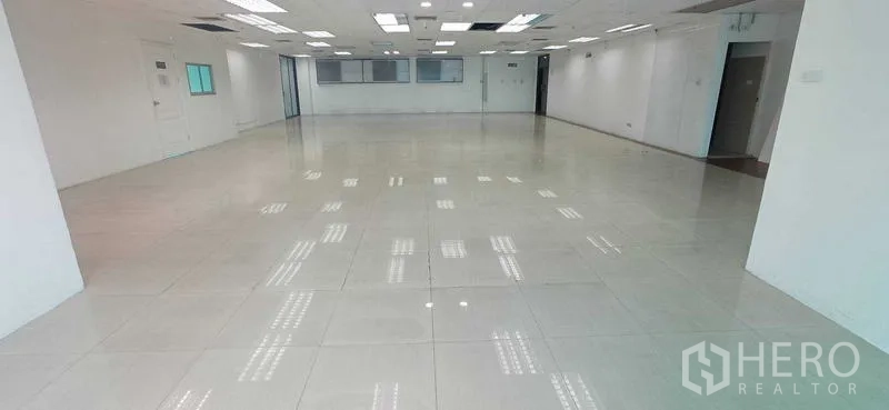 Office Space for rent in Huai Khwang, Bangkok - Central view of empty office featuring tiled flooring, recessed lighting and multiple entry points.