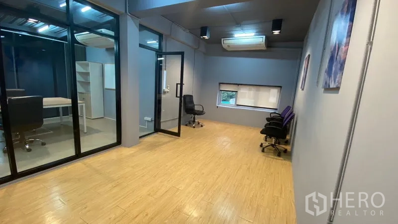 Office Space for rent in Sathon, Bangkok - Open room with wood floors, air conditioning, and a glass door to a private office in a Sathon workspace.