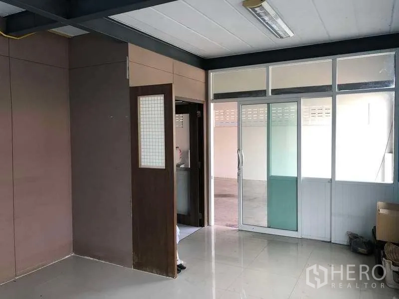Warehouse for rent in Pak Kret, Nonthaburi - Ground-floor office inside the warehouse with sliding glass doors, tiled floor and partition walls.