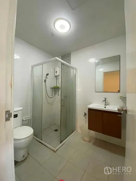 Townhouse for rent in Suan Luang, Bangkok - Modern bathroom with glass shower enclosure, toilet and vanity.