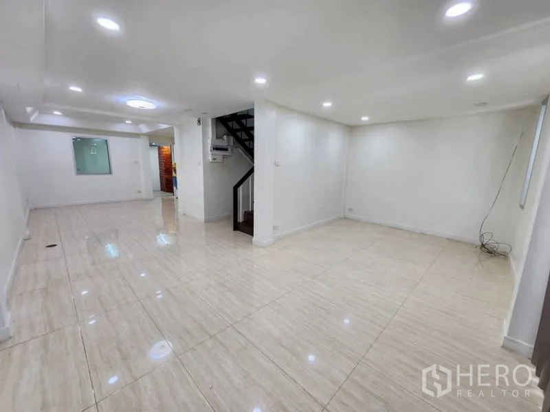 Home Office for rent in Khlong Toei, Bangkok - Spacious open-plan level with polished tiles, multiple ceiling spotlights, and a staircase leading to upper floors.