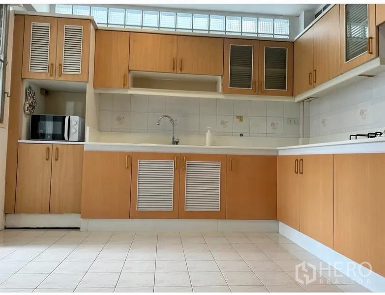 Home Office for rent in Suan Luang, Bangkok - L-shaped kitchen with light wood cabinets and tiled backsplash.