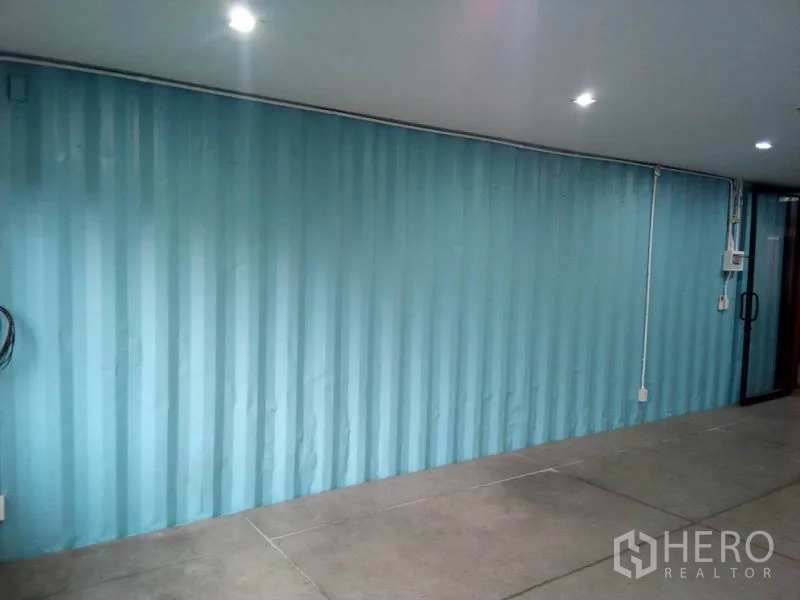Retail Space for rent in Khlong Toei, Bangkok - Bright retail room with blue corrugated wall and glass door entry.