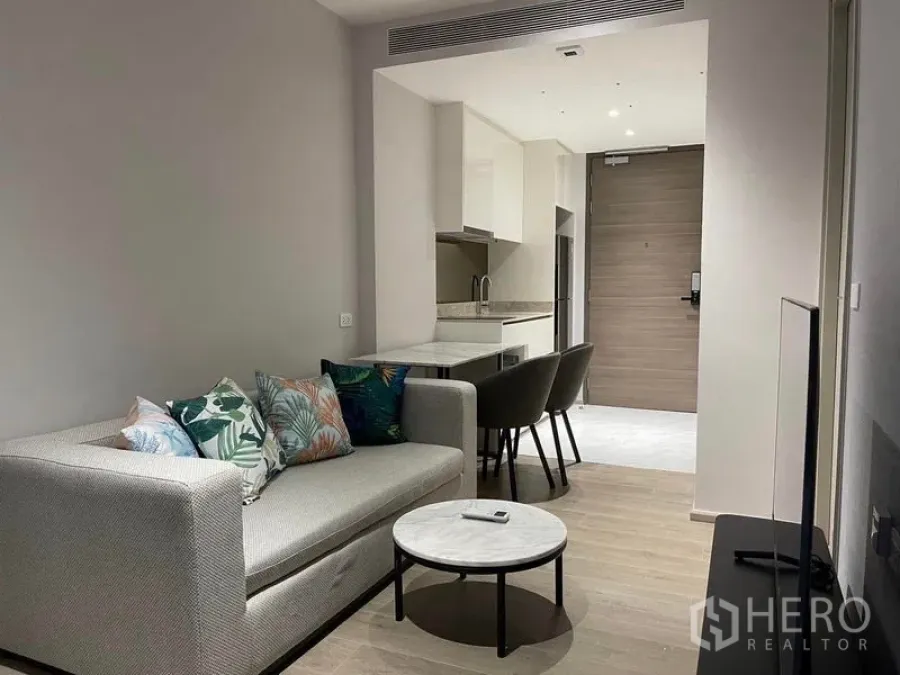 Condominium for rent in Khlong Toei, Bangkok - Open-plan living with sofa, dining seating and compact kitchen near entry