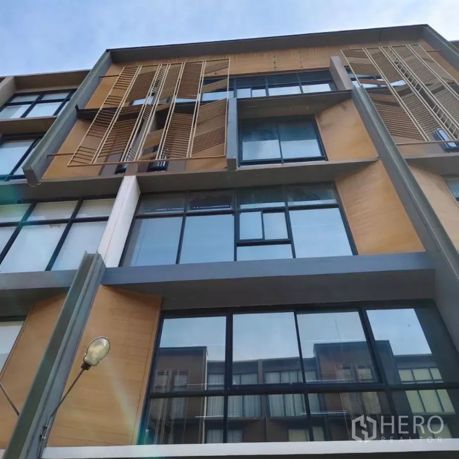 Home Office for rent or sale in Watthana, Bangkok - Modern multi-storey home office facade with large glass windows and wooden louver panels.