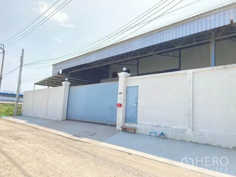 Warehouse for rent in Bang Phli, Samut Prakan - Gated warehouse exterior with high concrete wall and blue sliding metal door in Bang Phli.
