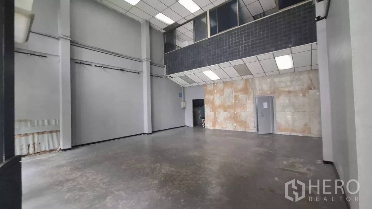 Shophouse for rent in Watthana, Bangkok - Open double-height hall with mezzanine and a tiled accent wall.
