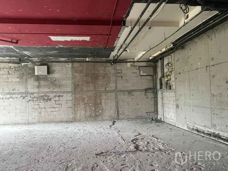 Retail Space for rent in Watthana, Bangkok - Utility wall with exposed MEP lines and electrical box inside unfinished retail space.