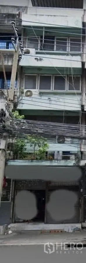 อาคารพาณิชย์ ขายในWatthana, Bangkok - ด้านหน้าตึกแถวหลายชั้นในกรุงเทพฯ พร้อมประตูม้วน ระเบียง และสายไฟริมถนน ใกล้ BTS เอกมัย.