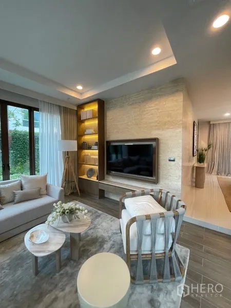 Detached House for sale in Bang Kapi, Bangkok - Cozy lounge area with TV wall, illuminated built-in shelving and contemporary seating.
