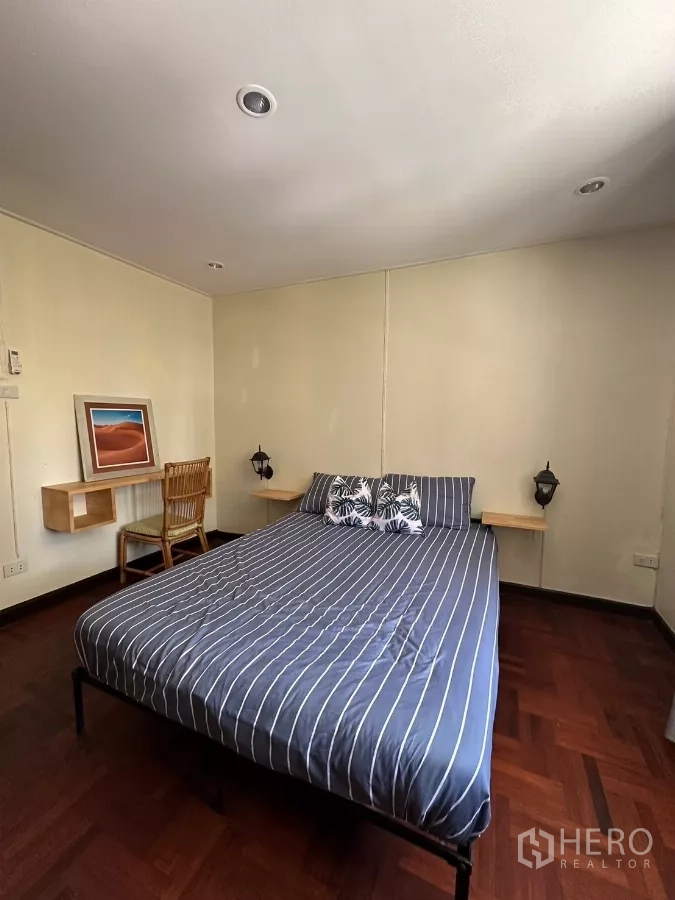 Home Office for rent in Suan Luang, Bangkok - Bedroom with striped bedding and a study desk.