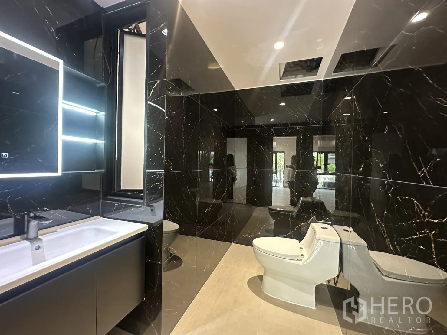 Home Office for rent in Watthana, Bangkok - Bathroom with black marble tiles, backlit mirror and modern sanitaryware.