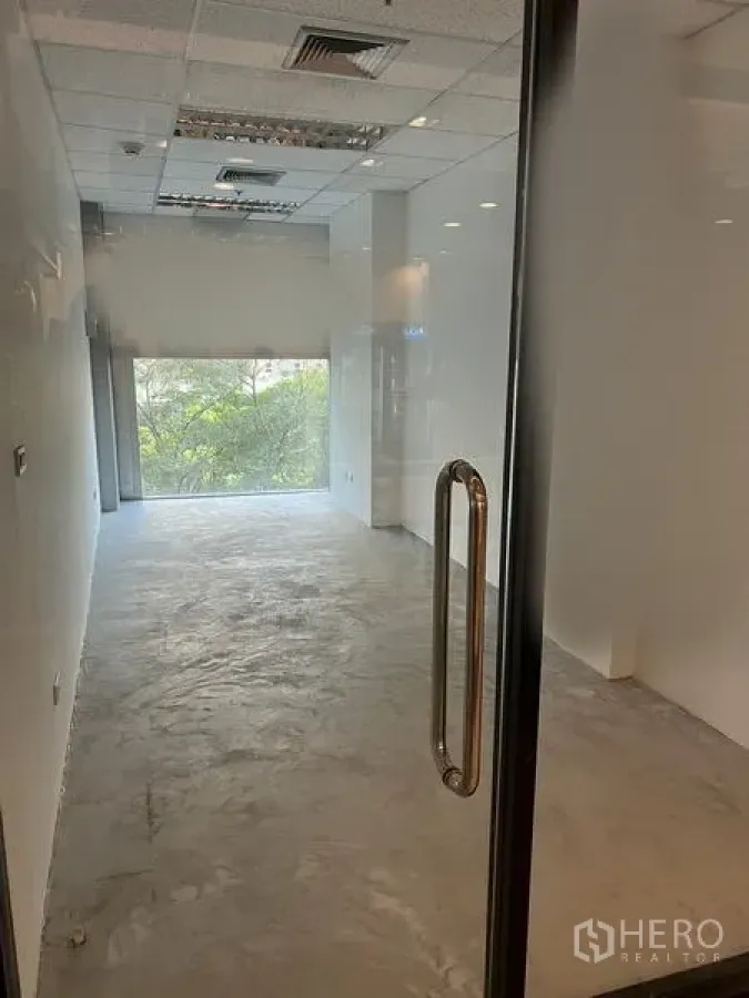 Retail Space for rent in Bang Rak, Bangkok - Compact retail unit with glass door, polished concrete floor, white walls, suspended ceiling and a large window with leafy views in Silom, Bang Rak.