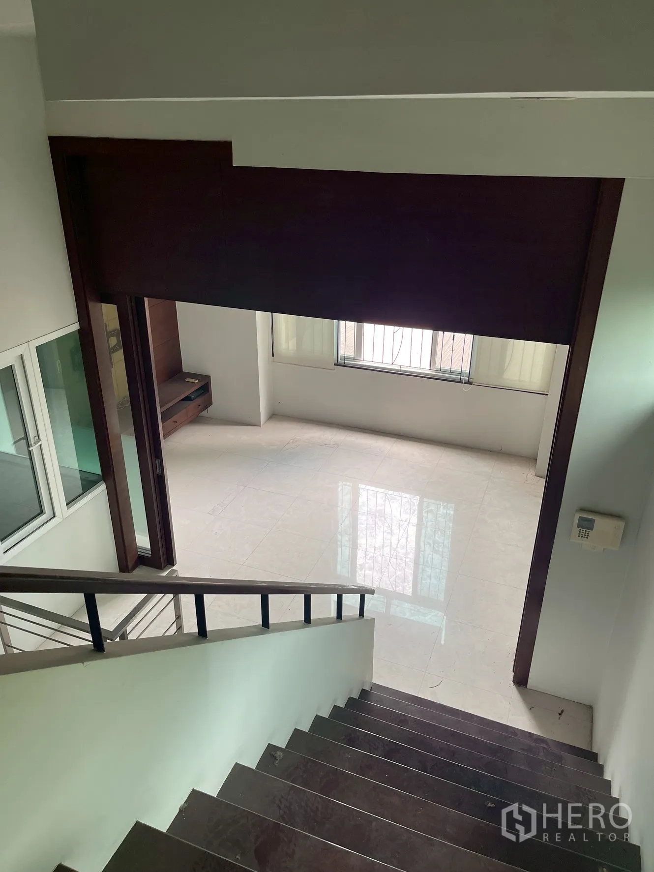 Home Office for rent in Wang Thonglang, Bangkok - View down stairs to open-plan room with glossy tile floors and window.