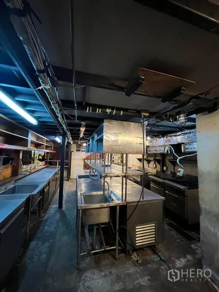 Retail Space for rent in Watthana, Bangkok - Commercial kitchen with stainless-steel sinks, prep counters, exhaust hood and exposed piping.