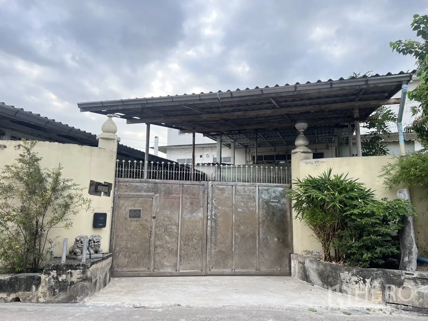 Warehouse for rent in Phra Pradaeng, Samut Prakan - Gated warehouse entrance with metal gate, perimeter wall, and a large covered canopy.