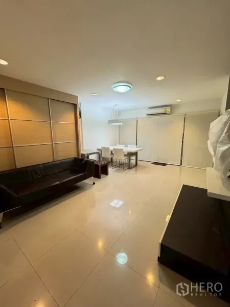Townhouse for rent in Suan Luang, Bangkok - Spacious living room with glossy tiles, sofa and dining set with window blinds.
