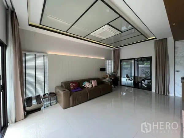 联排别墅 出租在Saphan Sung, Bangkok - 宽敞客厅，亮面地砖、嵌灯天花和推拉门通向庭院。