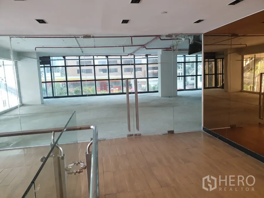 Retail Space for rent in Watthana, Bangkok - Glass double-door entrance with mirrored wall and wood flooring leading into a bright retail space with large windows.