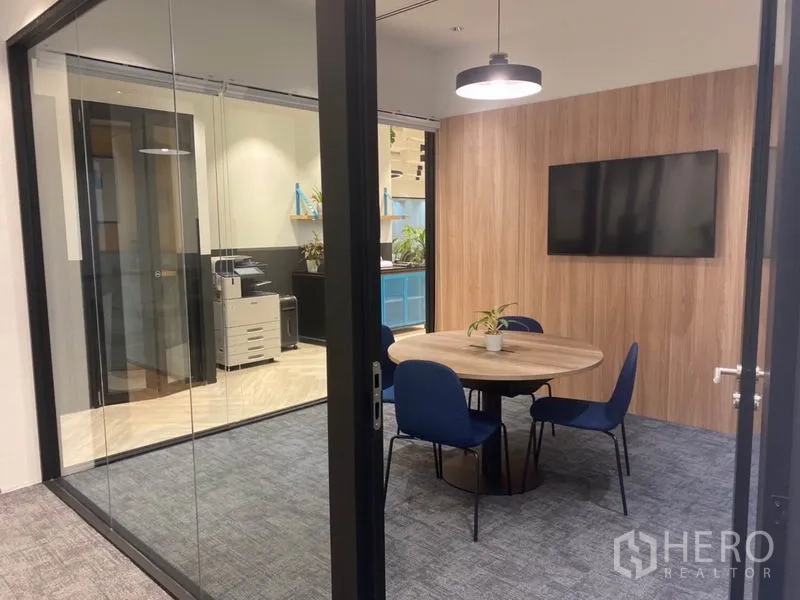 Office Space for rent in Pathum Wan, Bangkok - Glass-walled meeting room with round table, TV and a view to the printer area.