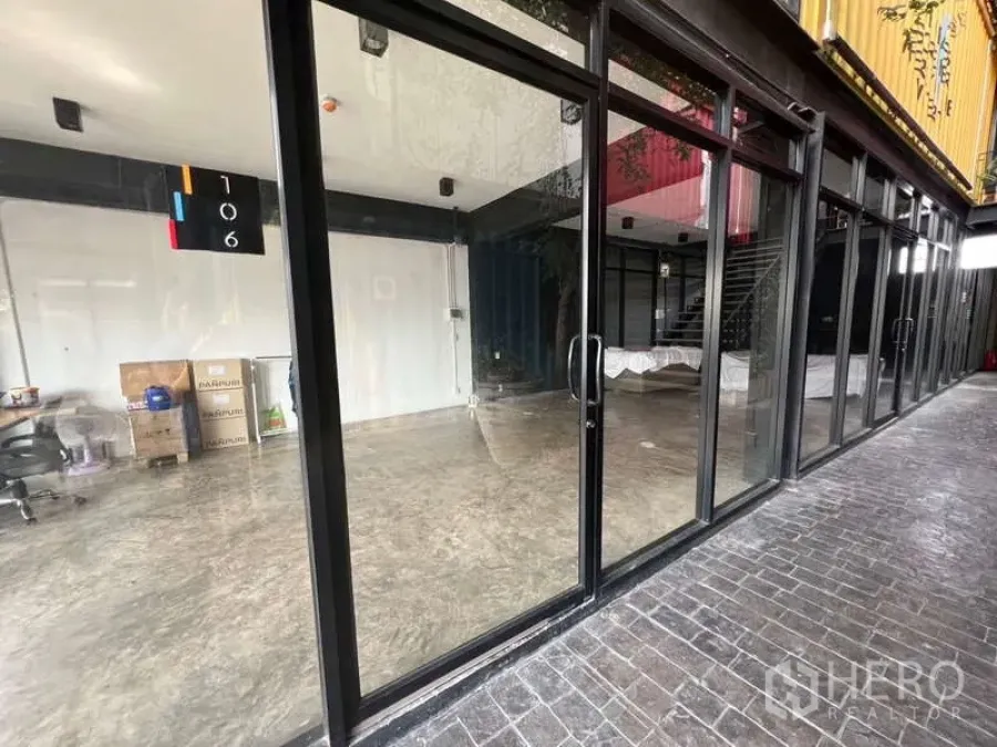 Retail Space for rent - Glass-fronted retail unit with black metal frames and polished concrete floor along a covered walkway.