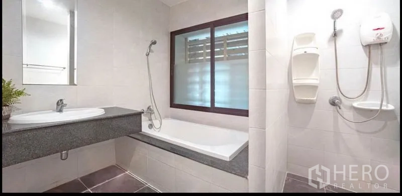 Townhouse for sale in Khlong Toei, Bangkok - Bathroom with bathtub, separate shower, window ventilation and stone countertop vanity.