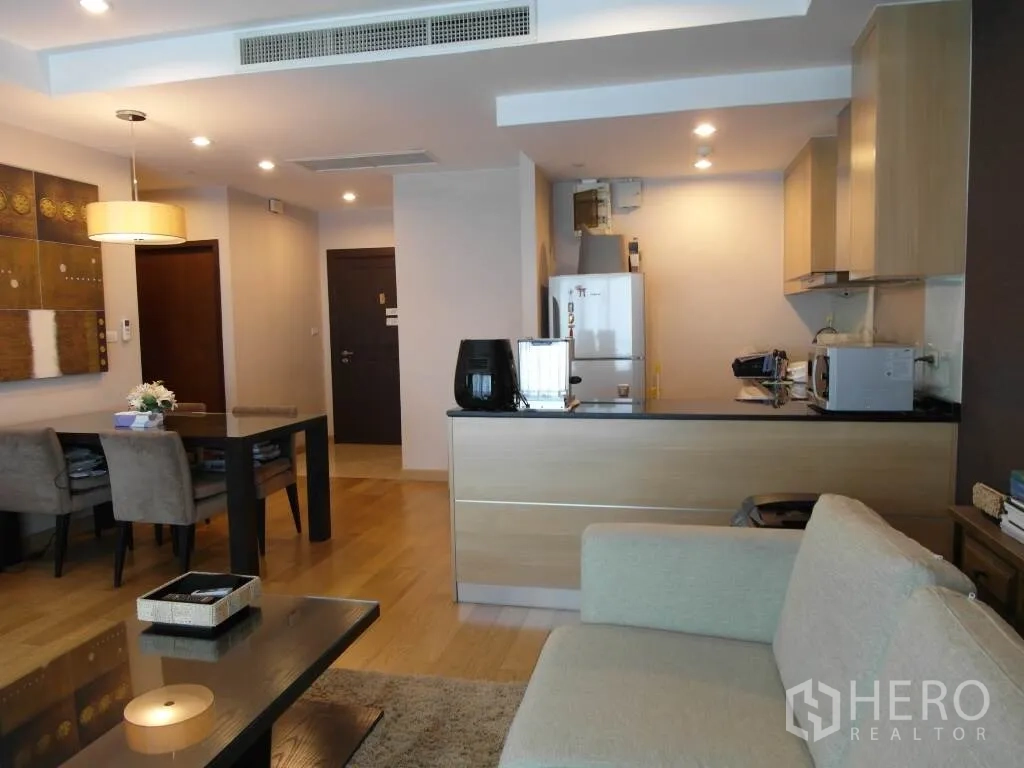 Condominium for rent or sale in Sathon, Bangkok - Bright lounge facing a built-in kitchen with light wood cabinets, dining table and entry hallway.