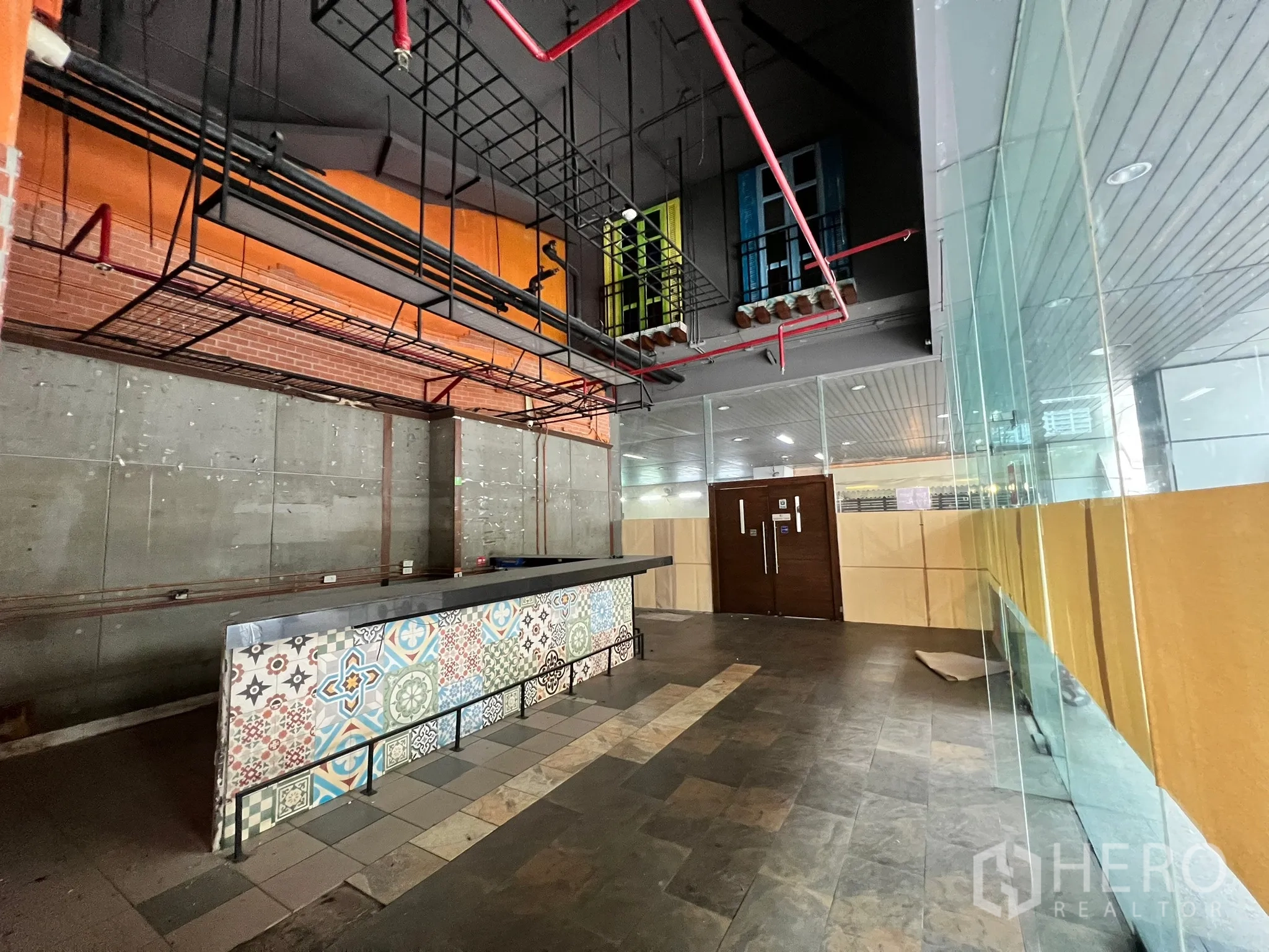 Retail Space for rent in Watthana, Bangkok - Bar counter beside glass frontage and wood doors with metal hanging racks and exposed ceiling pipes.