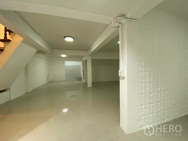独立式住宅 出租在Bang Na, Bangkok - 明亮宽敞的客厅视角，带立柱、吸顶灯和纹理装饰墙。