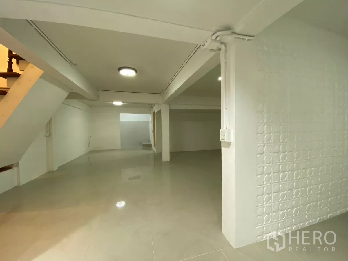 独立式住宅 出租在Bang Na, Bangkok - 明亮宽敞的客厅视角，带立柱、吸顶灯和纹理装饰墙。