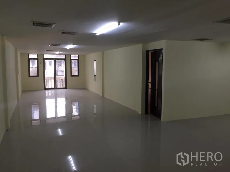 Home Office for rent in Watthana, Bangkok - Spacious unfurnished open‑plan floor with glossy tiles, multiple windows and balcony doors.