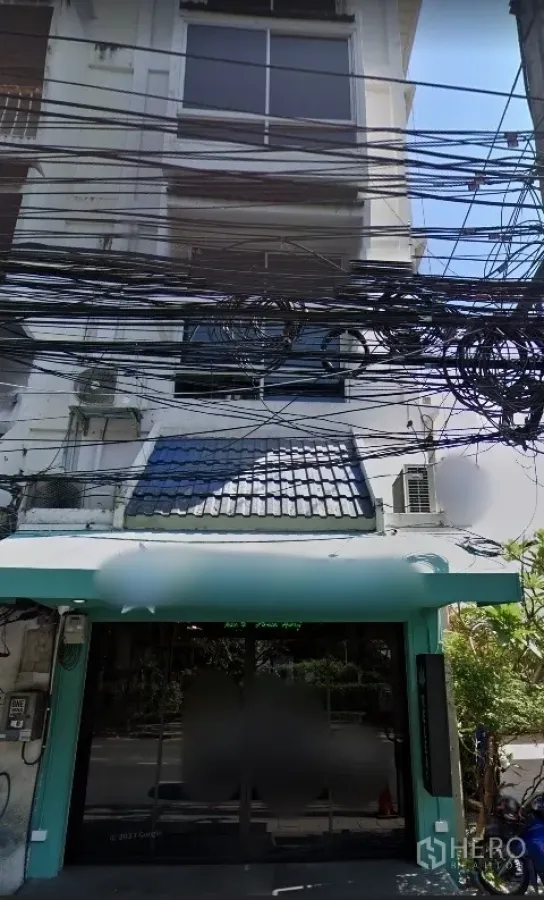 อาคารพาณิชย์ ให้เช่าในWatthana, Bangkok - ด้านหน้าอาคารพาณิชย์หลายชั้น หน้ากระจก กันสาดสีเขียวมิ้นต์ และสายไฟเหนือถนน ในย่านเอกมัย วัฒนา
