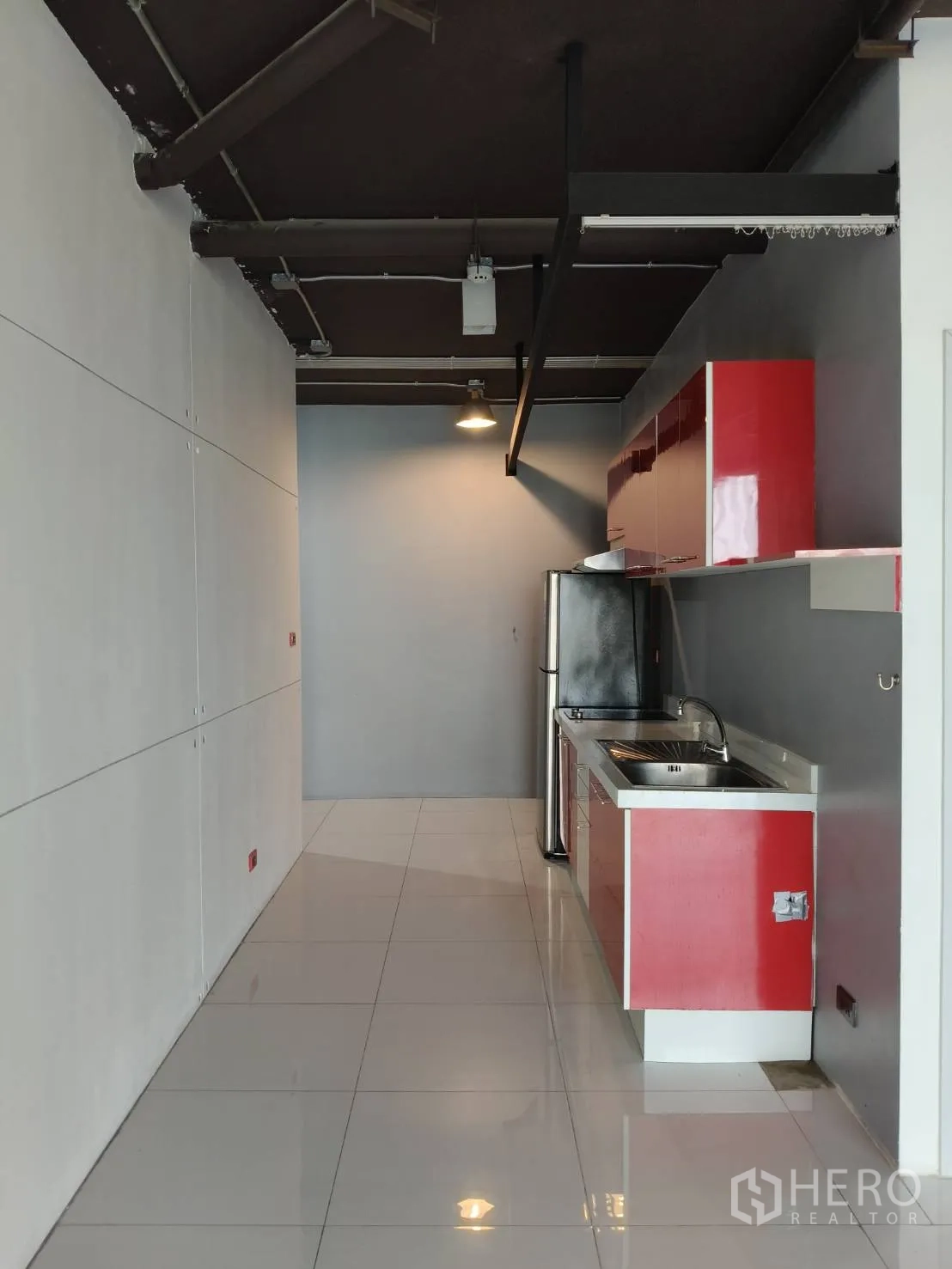 Office Space for rent in Khlong Toei, Bangkok - Long galley workspace featuring glossy tiles and red cabinetry with a stainless sink.