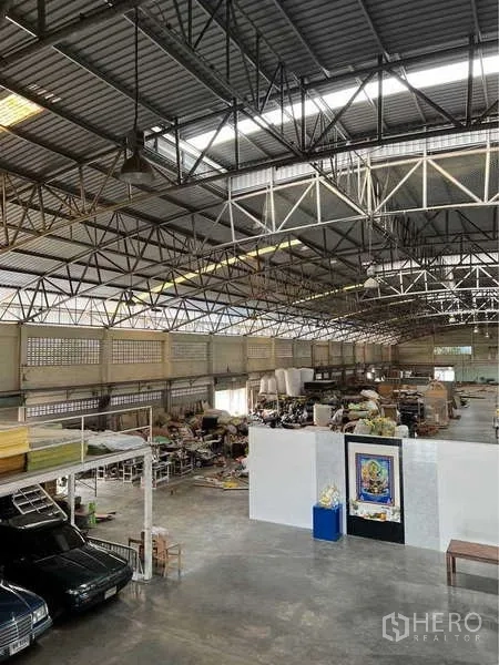 Warehouse for sale in Bang Bua Thong, Nonthaburi - Spacious warehouse interior with steel truss roof, skylights and organized storage zones.