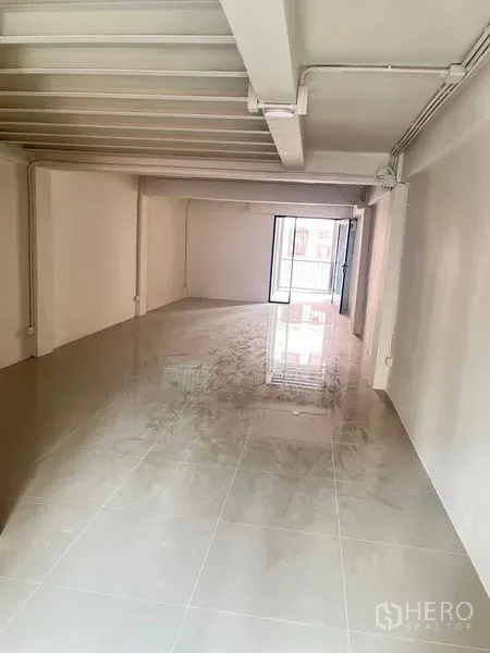 Retail Space for rent - Long open‑plan retail floor with glossy tiles and exposed ceiling beams.