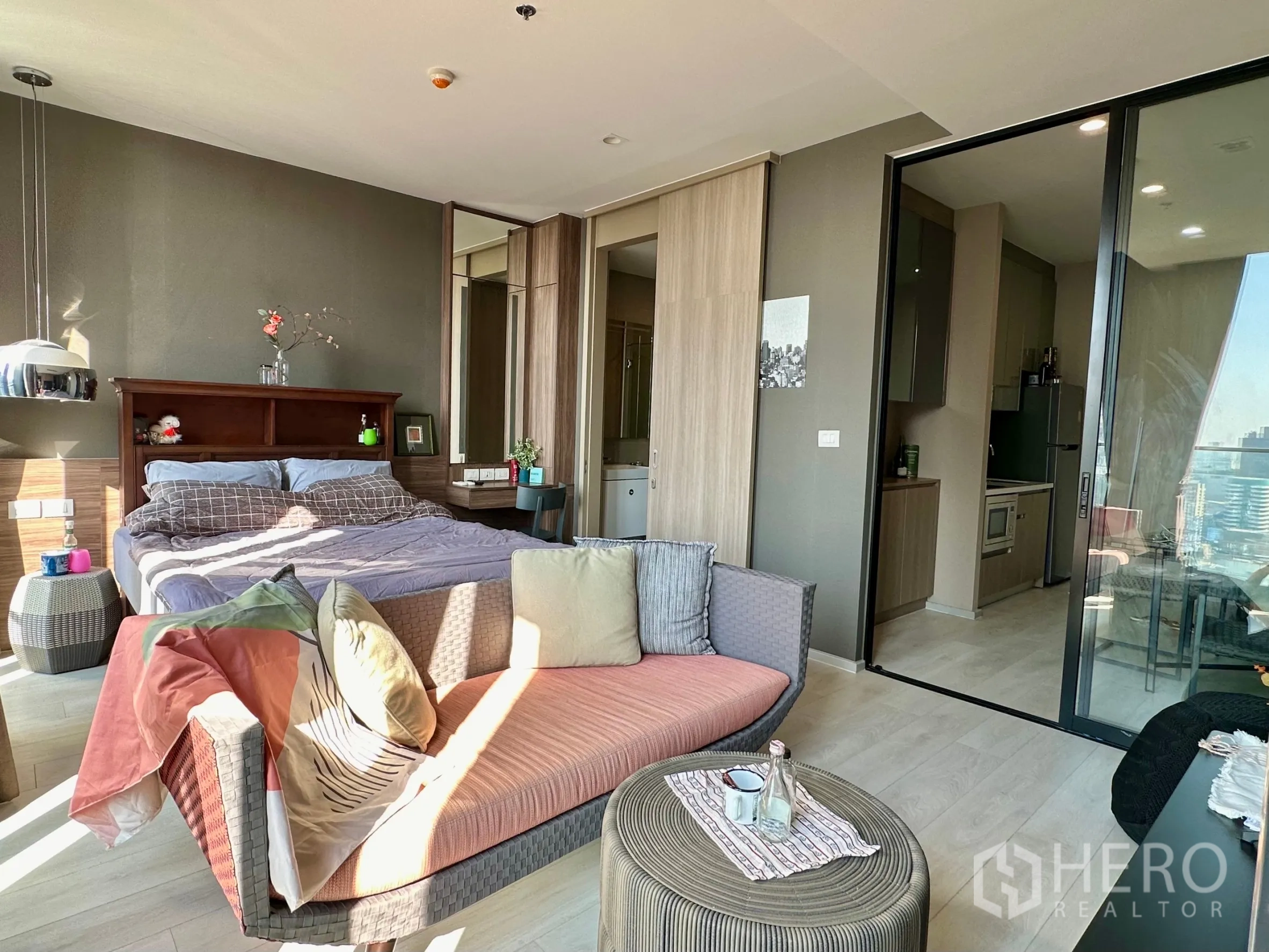 Condominium for rent in Pathum Wan, Bangkok - Cozy sleeping area with sofa and sliding glass door to a separate kitchen.